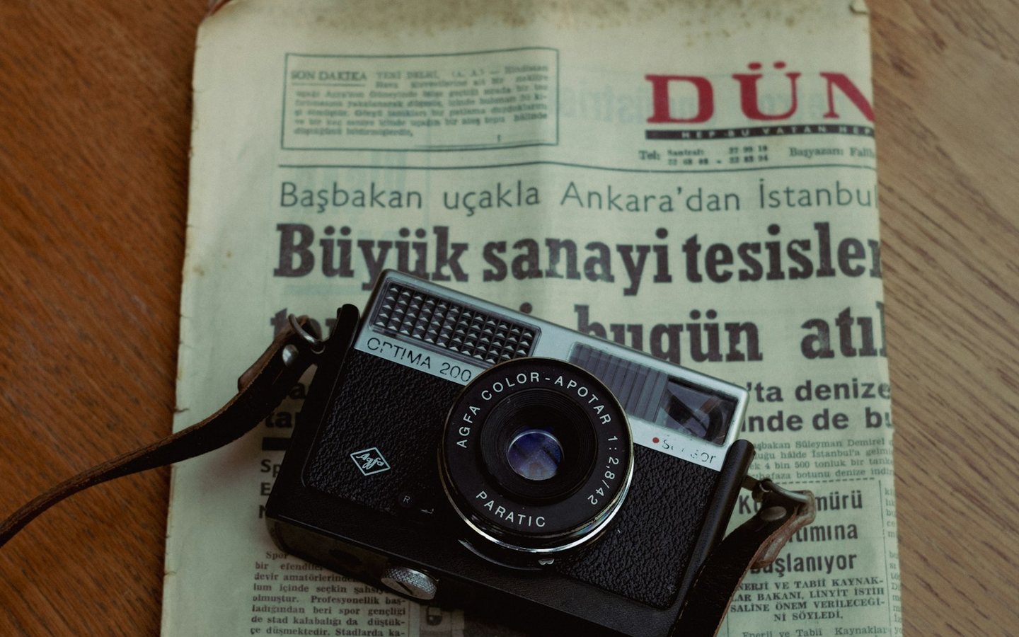 Ahşap masa üzerinde gazete ve analog fotoğraf makinesi