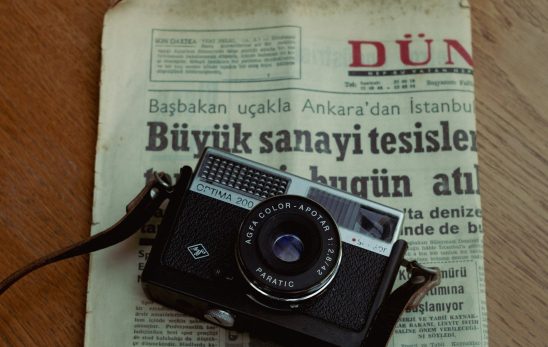 Ahşap masa üzerinde gazete ve analog fotoğraf makinesi